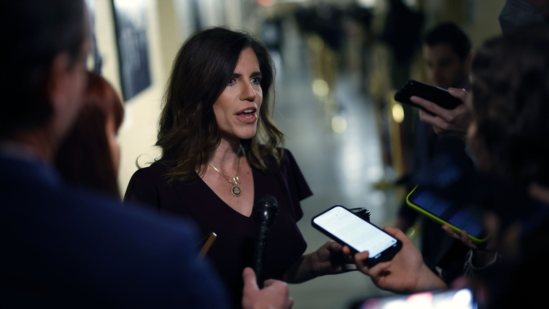 Rep. Nancy Mace, wearing a black dress and speaking to reporters in a hallway.