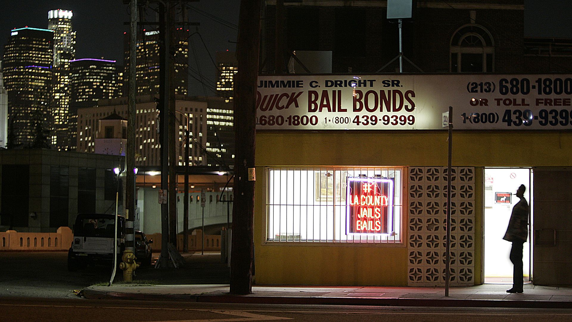 The lights of downtown Los Angeles shine behind a Quick Bail Bonds building across from the Men's Central Jail. 