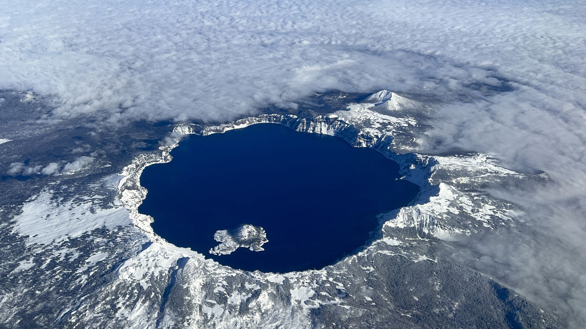 An aerial image shows Crater Lake National Park under a blanket of snow.