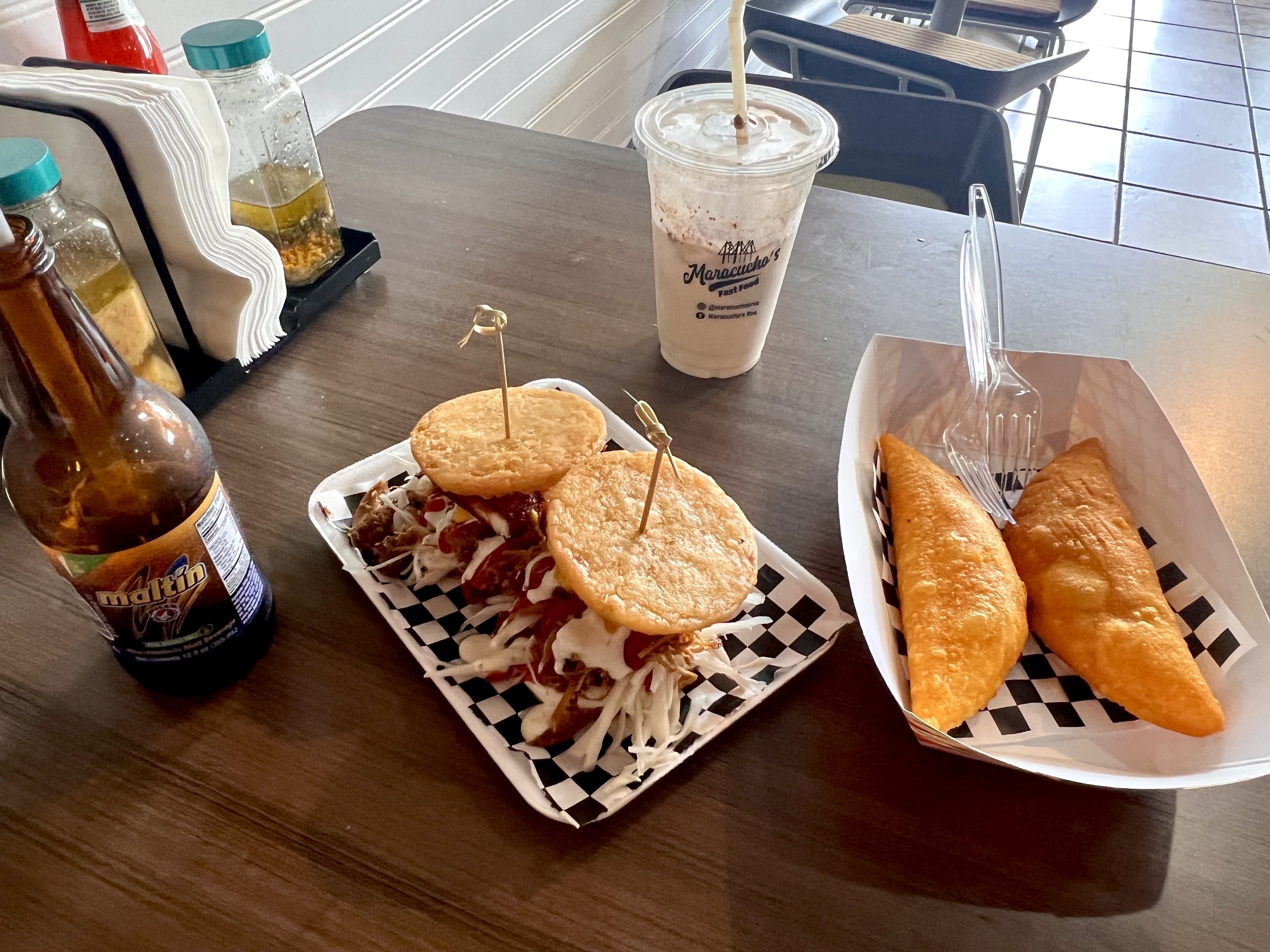 A spread of maltin polar, arepas, chicha and empanadas