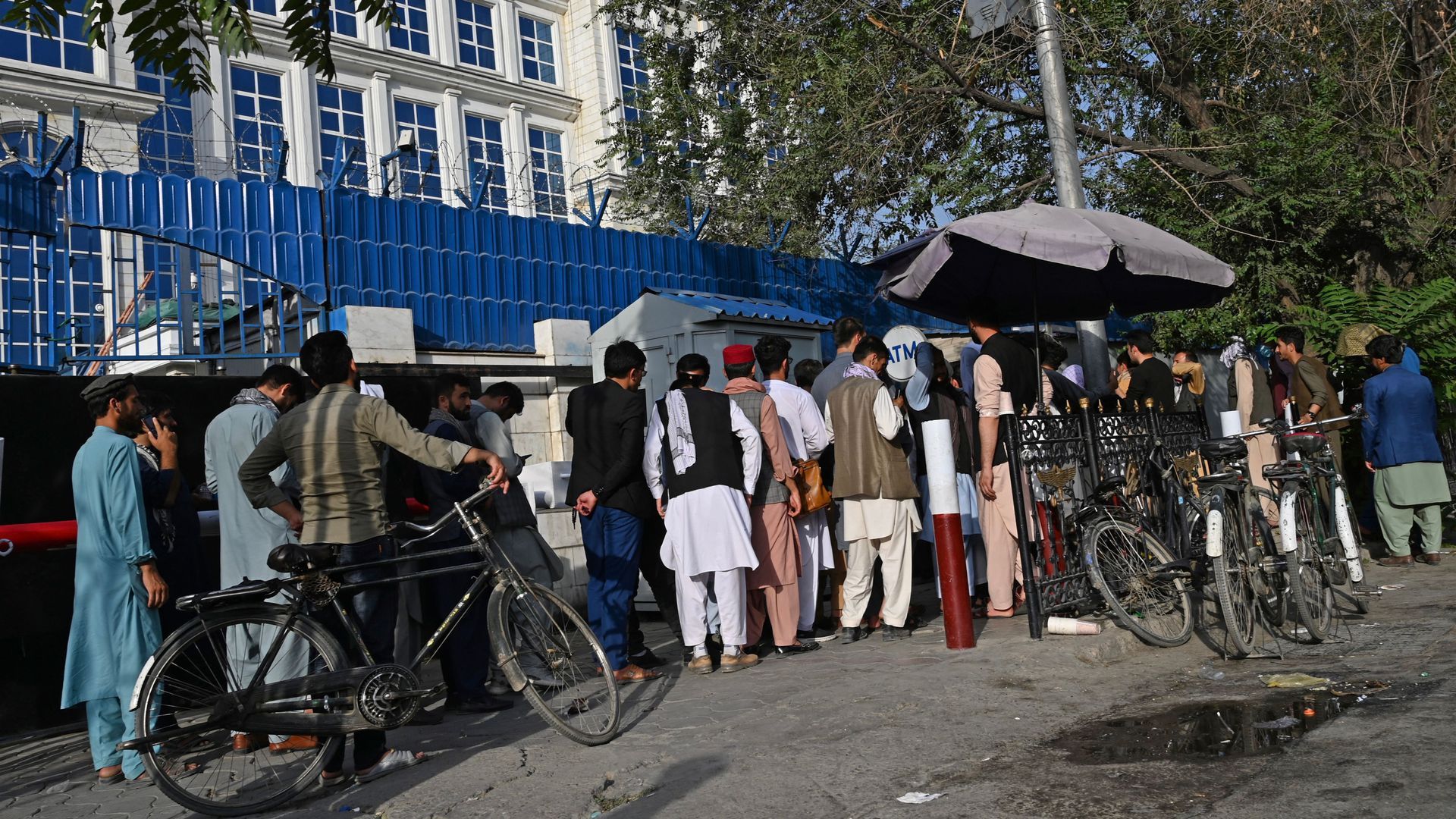 A crowd of Afghans lined up waiting their turn at an ATM outside a building