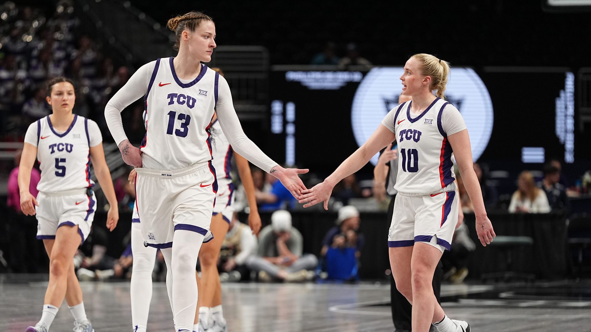 Two women tap hands during a basketball game
