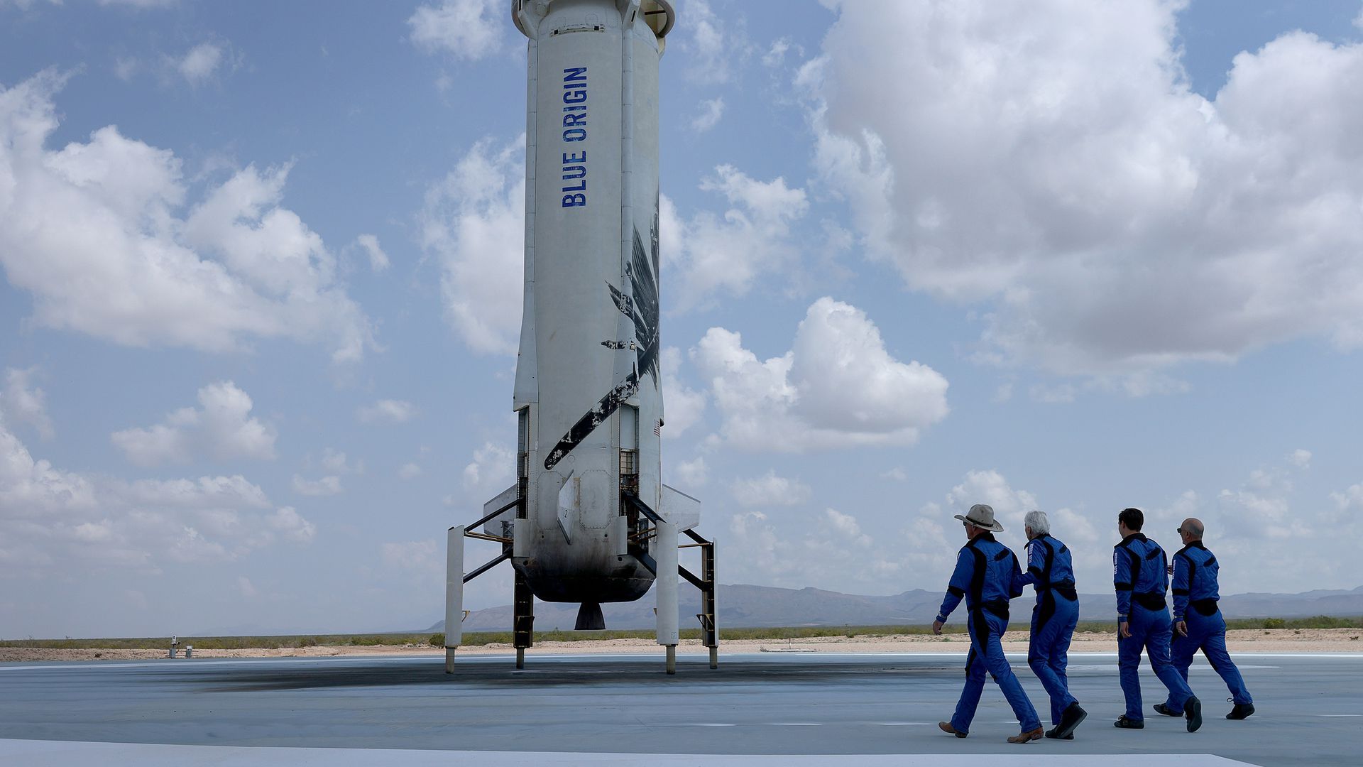 Caption: Blue Origin’s New Shepard crew (L-R) Jeff Bezos, Wally Funk, Oliver Daemen, and Mark Bezos walk near the booster (Photo by Joe Raedle/Getty Images)