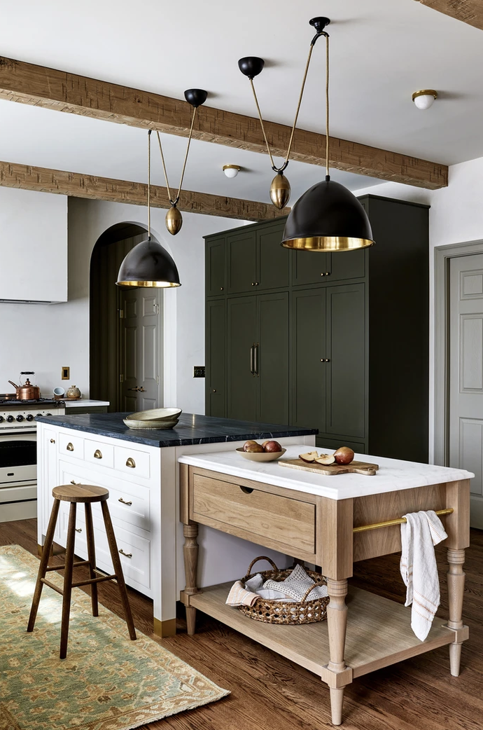 The main island is a creamy white with black counters, and the attached work station has white counters, a wood base and has a slightly lower profile. Photo: Stacy Zarin Goldberg