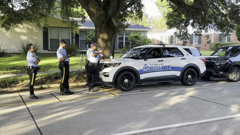 An SUV drives past a trio of New Orleans Police cops as one of them uses a radar gun on passing vehicles.