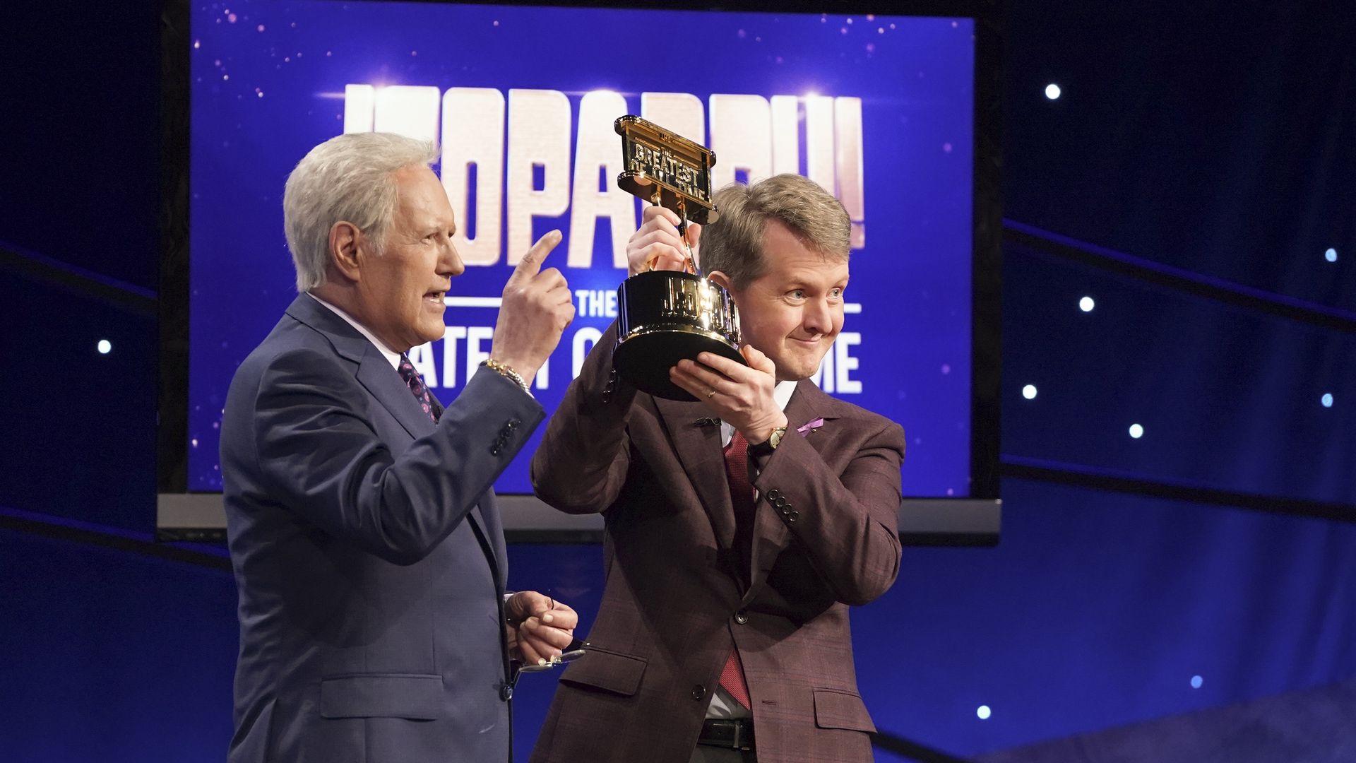 Alex Trebek and Ken Jennings hold up a trophy at  JEOPARDY! The Greatest of All Time