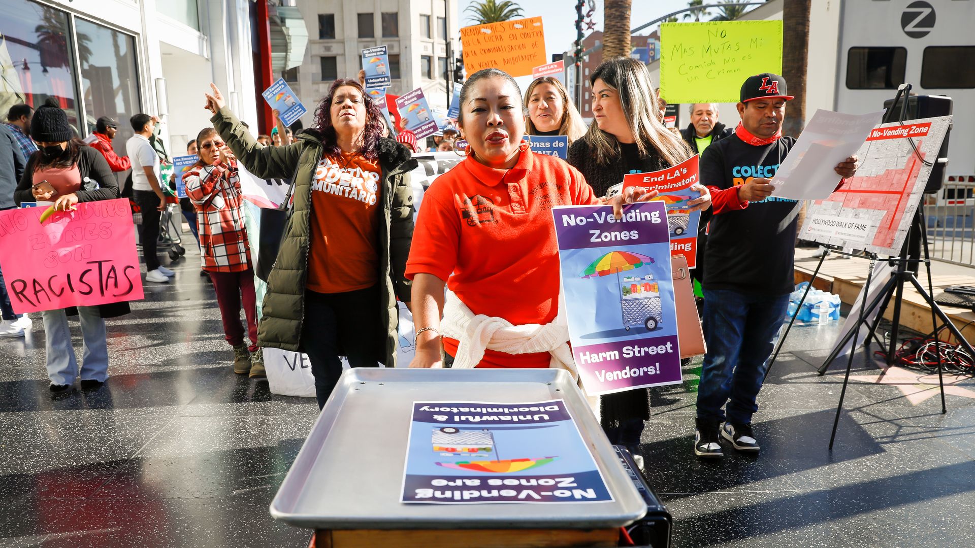 A group of protester walk through the Hollywood Walk of Fame holding signs and with their arms in the air 
