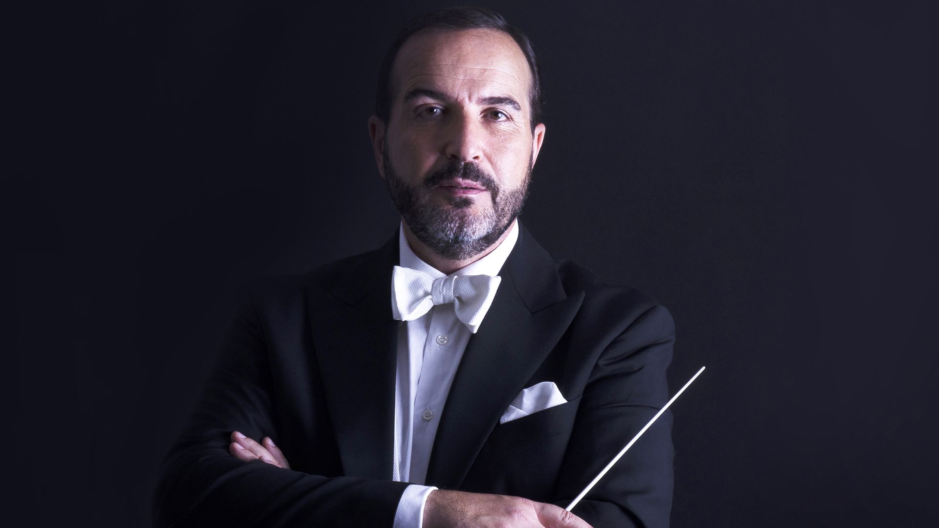 Opera Carolina musical director in a tux, holding a baton. 