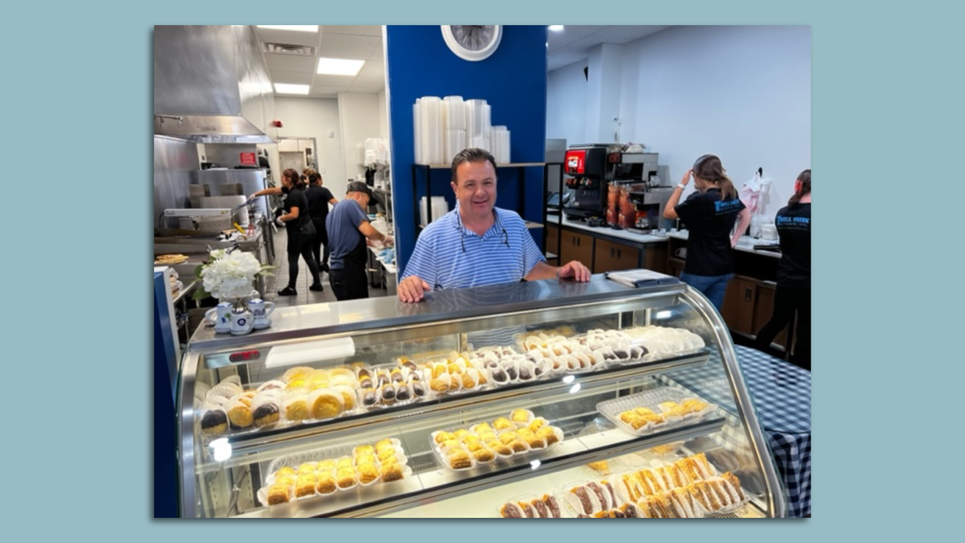 A man stands behind a bakery display filled with pastries