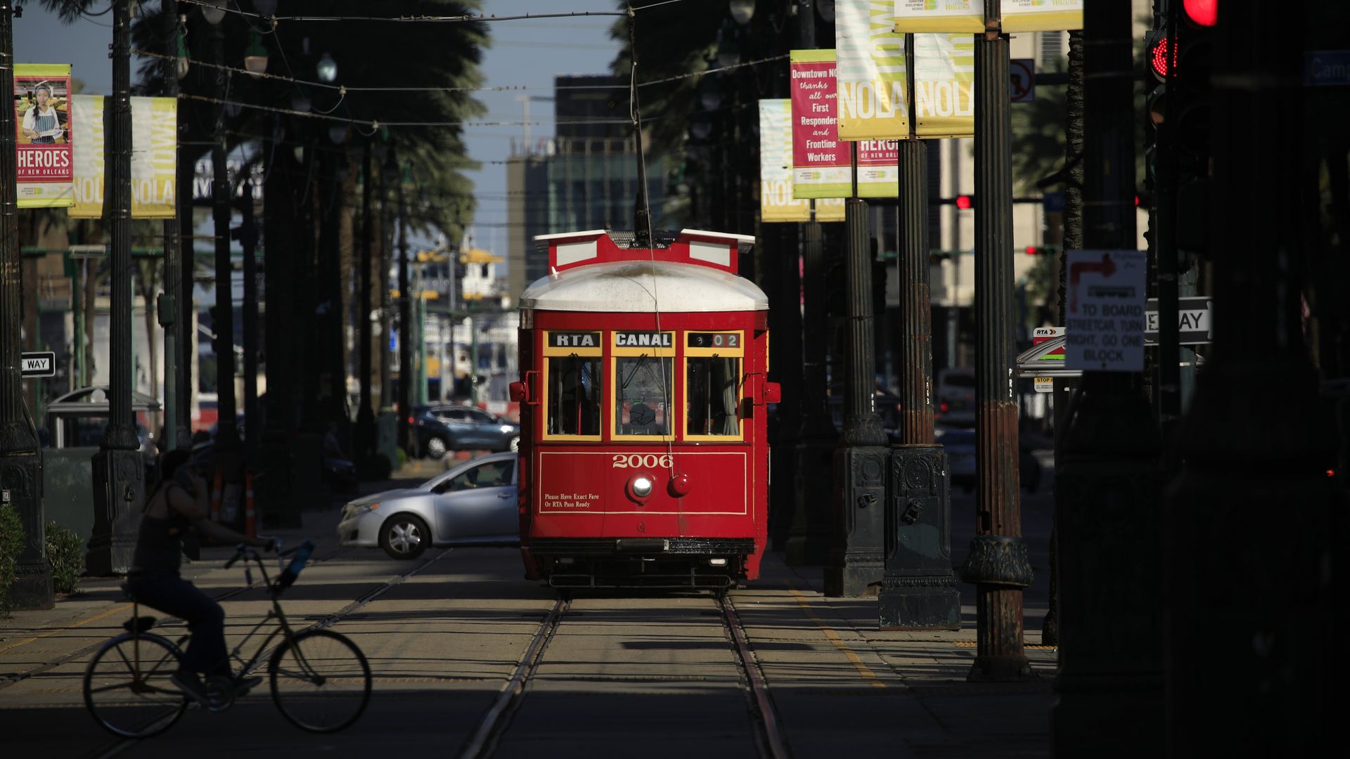 A red streetcar rolls down Canal Street. There are palm trees around it.