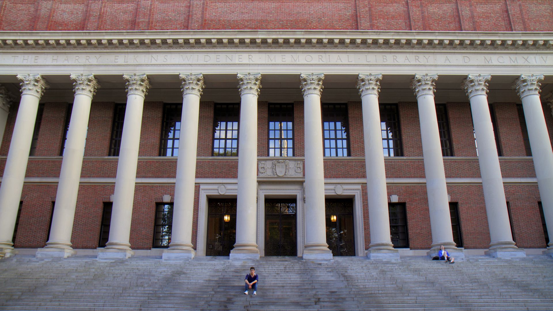 A student sits on concrete steps, wide shot