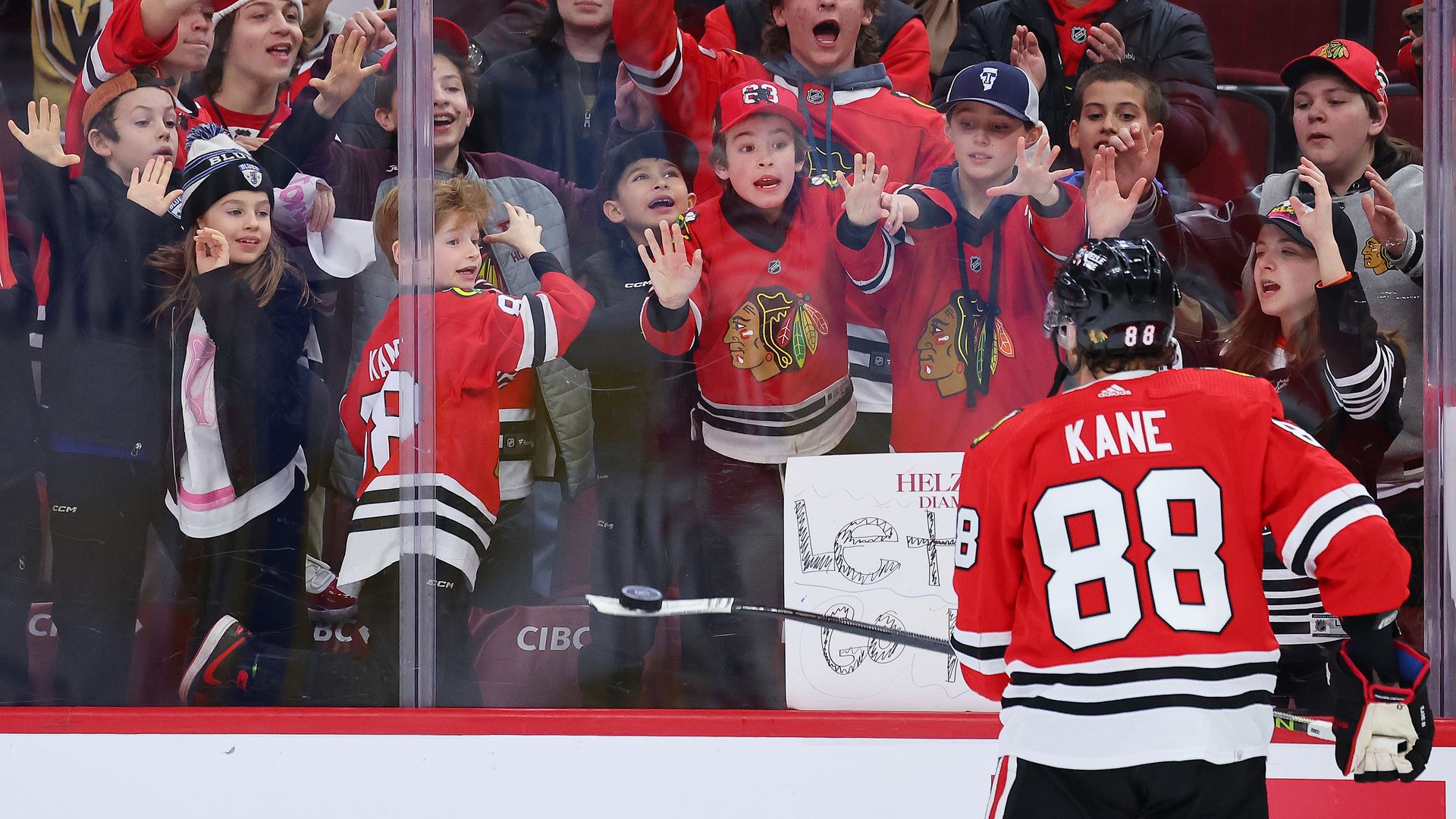 Photo of a hockey player skating by fans cheering
