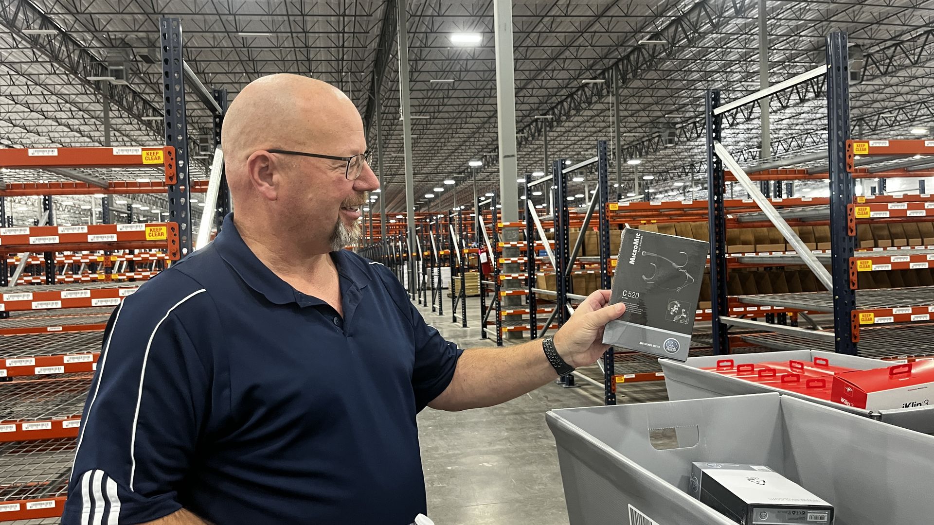 A man holding up a small portable microphone in a warehouse.