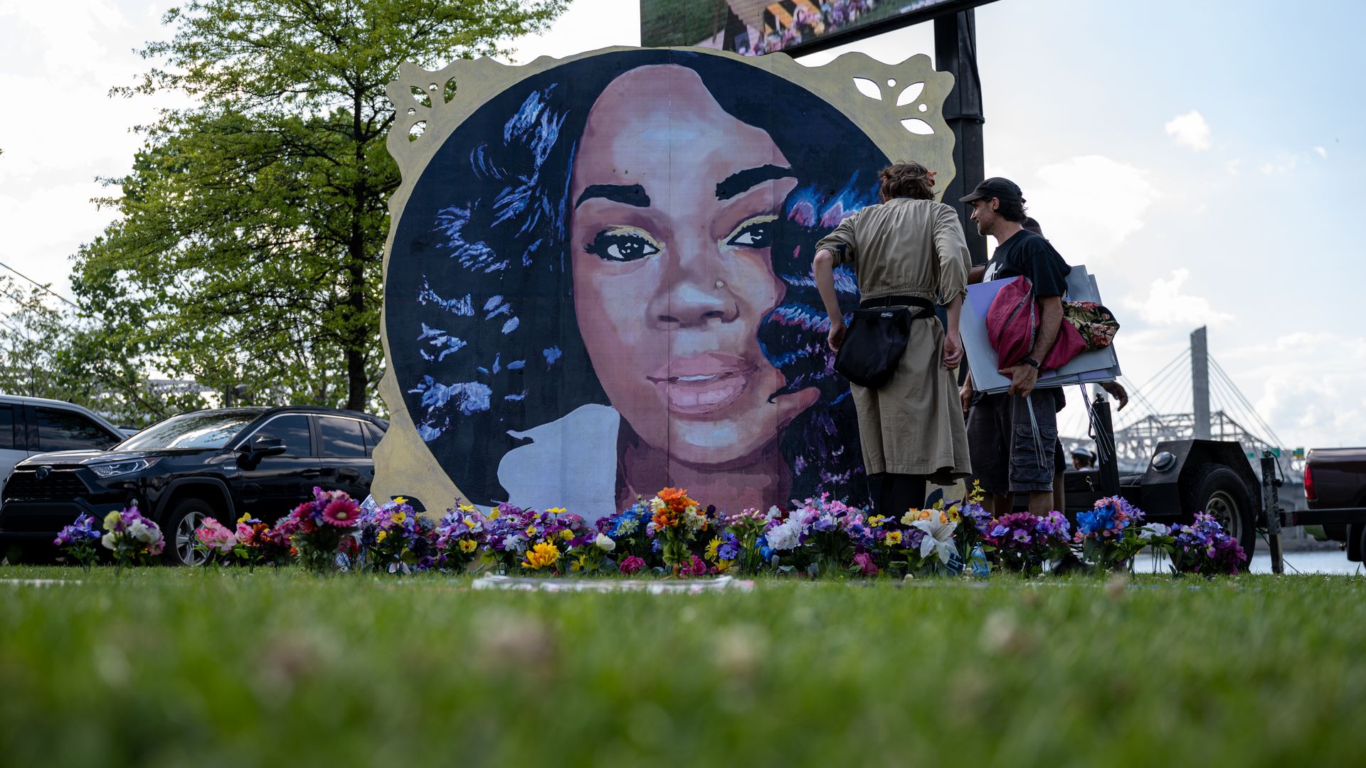Protesters and volunteers prepare a Breonna Taylor art installation by laying posters and flowers before the "Praise in the Park" event at the Big Four Lawn on June 5, 2021 in Louisville, Kentucky.