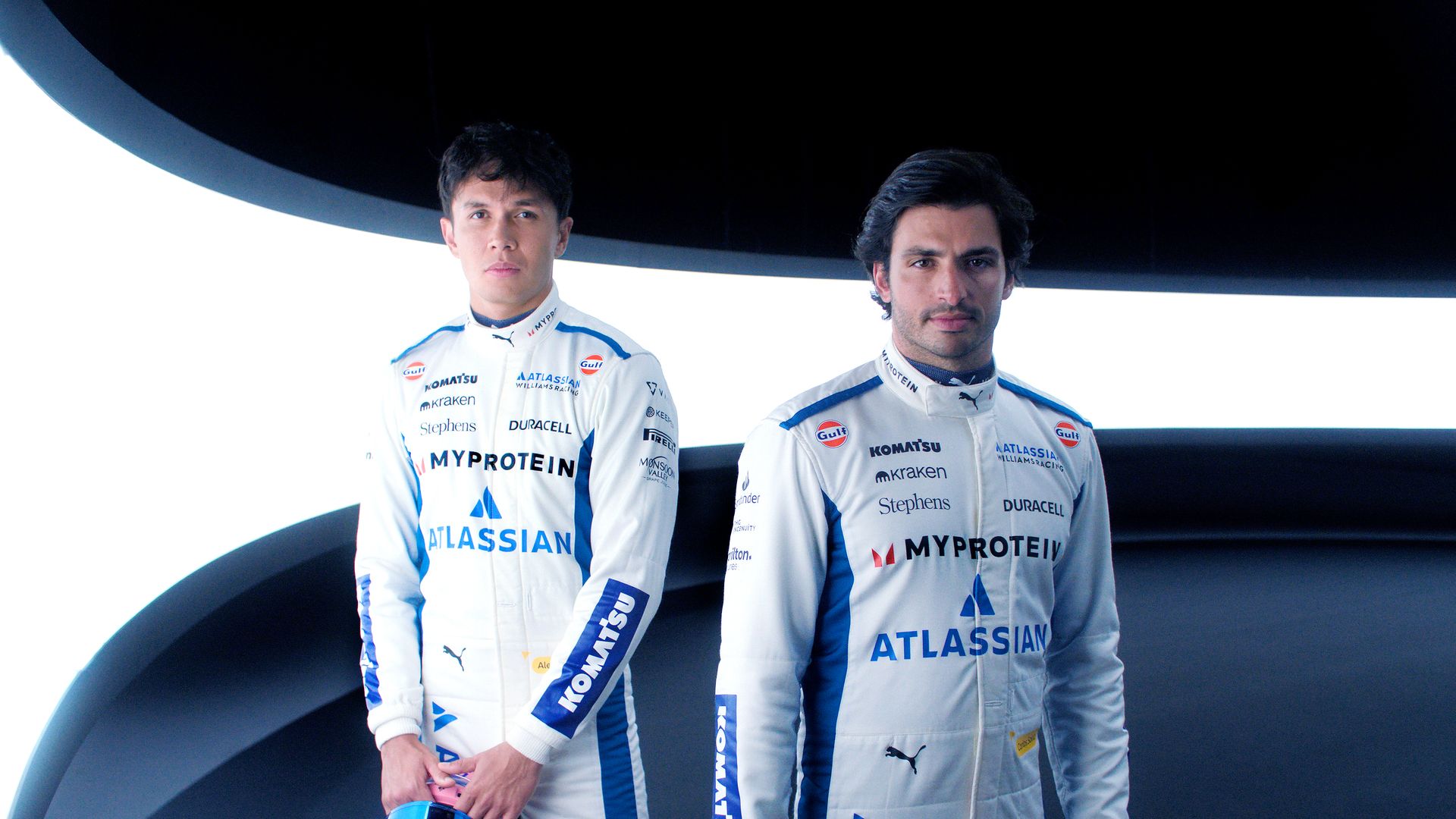 Two men in F1 racing gear.