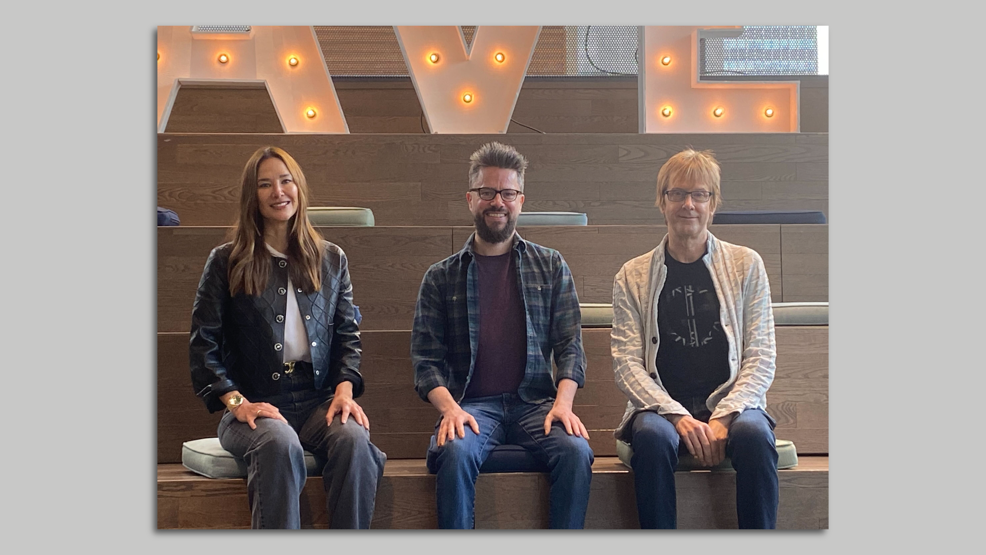 Photo of three people sitting on risers