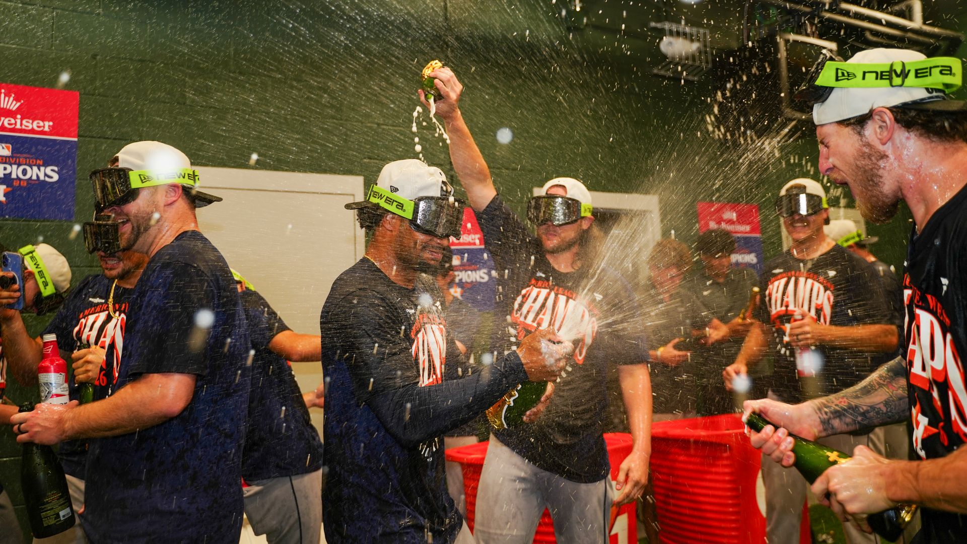 Group of men in Astros shirts celebrating, spraying champagne and wearing goggles.