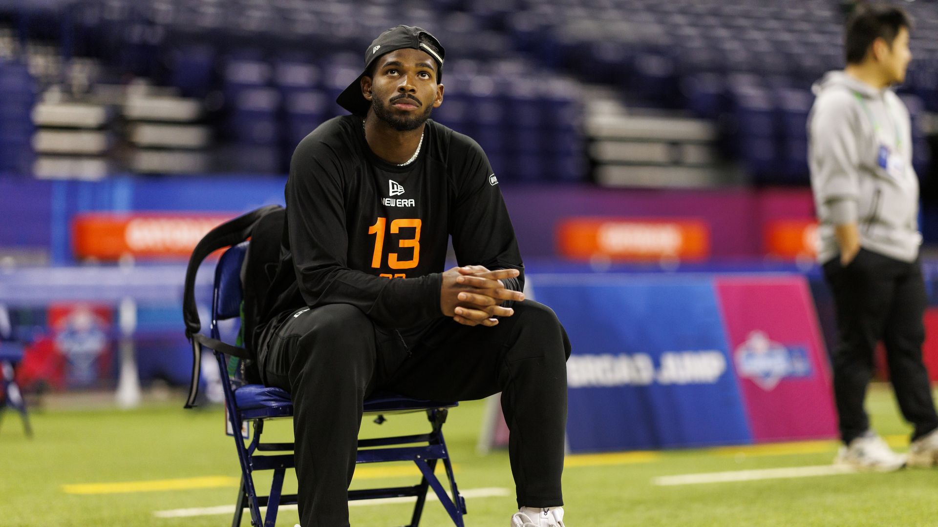 Colorado quarterback Shedeur Sander sits in a chair out of uniform on a football field.