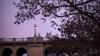 A bridge is bathed in purple light as a figure runs across it. 