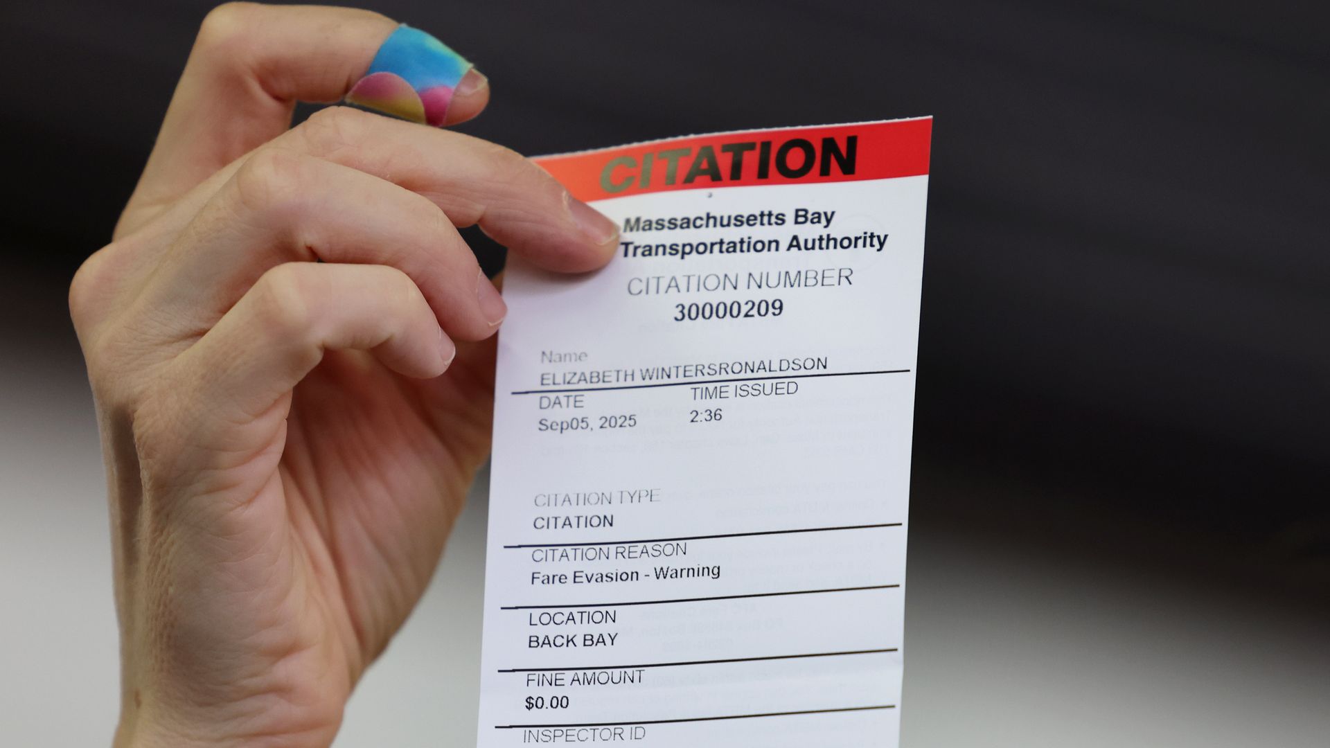 Hand holding a Massachusetts Bay Transportation Authority citation numbered 30000209 for fare evasion warning, issued on Sep 05, 2025 at 2:36 in Back Bay, with a $0.00 fine.