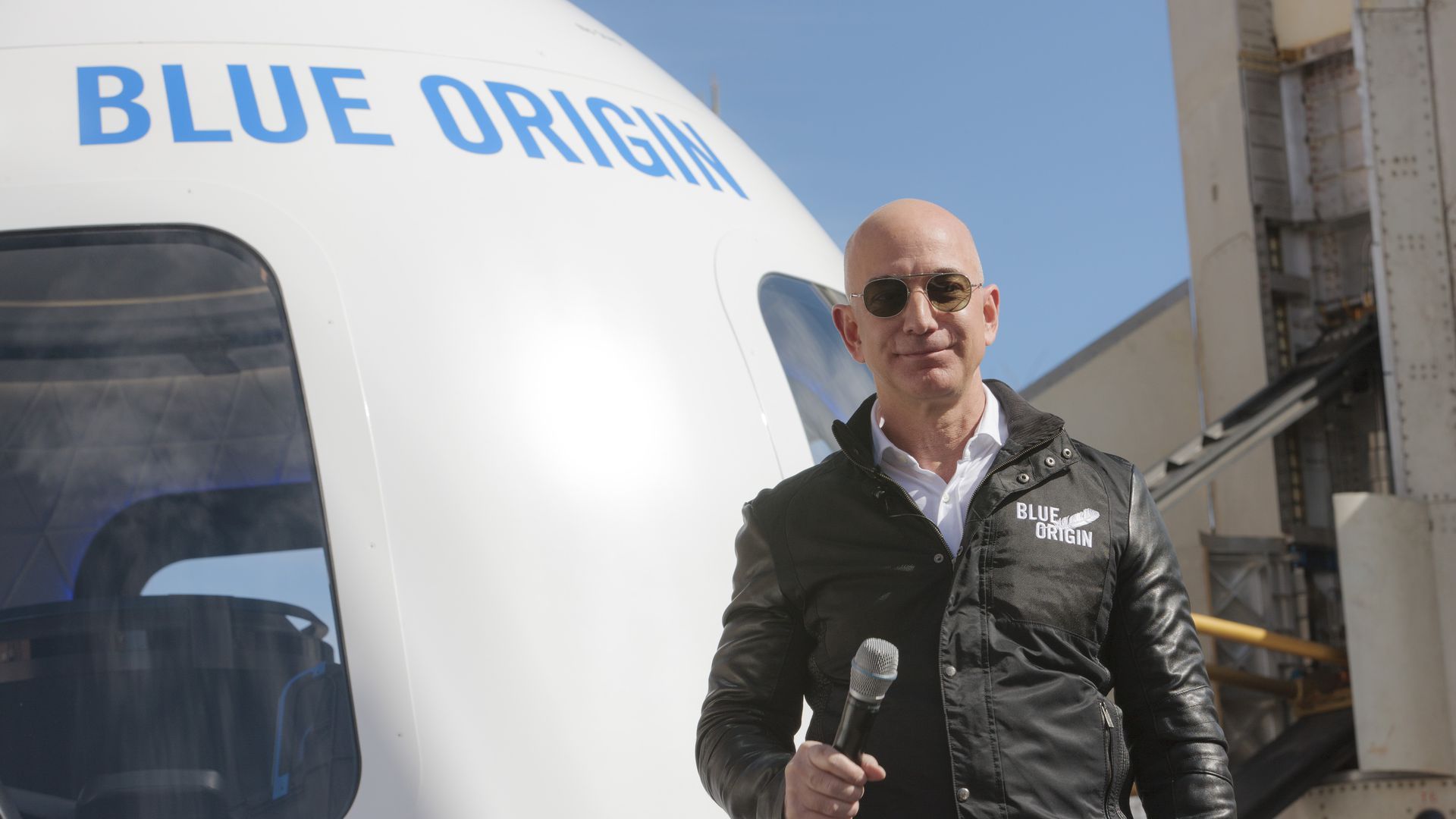 Photo of Jeff Bezos standing in front of a large vehicle with the words "Blue Origin" on it