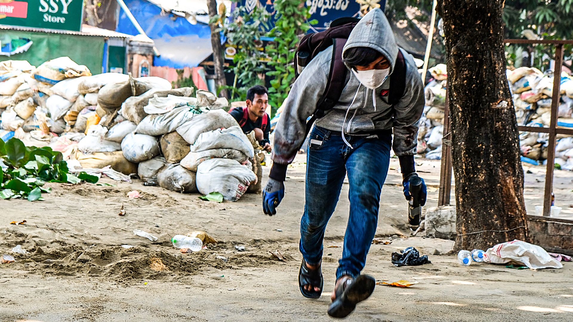 A protester runs past makeshift barricades during a demonstration against the military coup in Yangon's Thaketa township on March 29