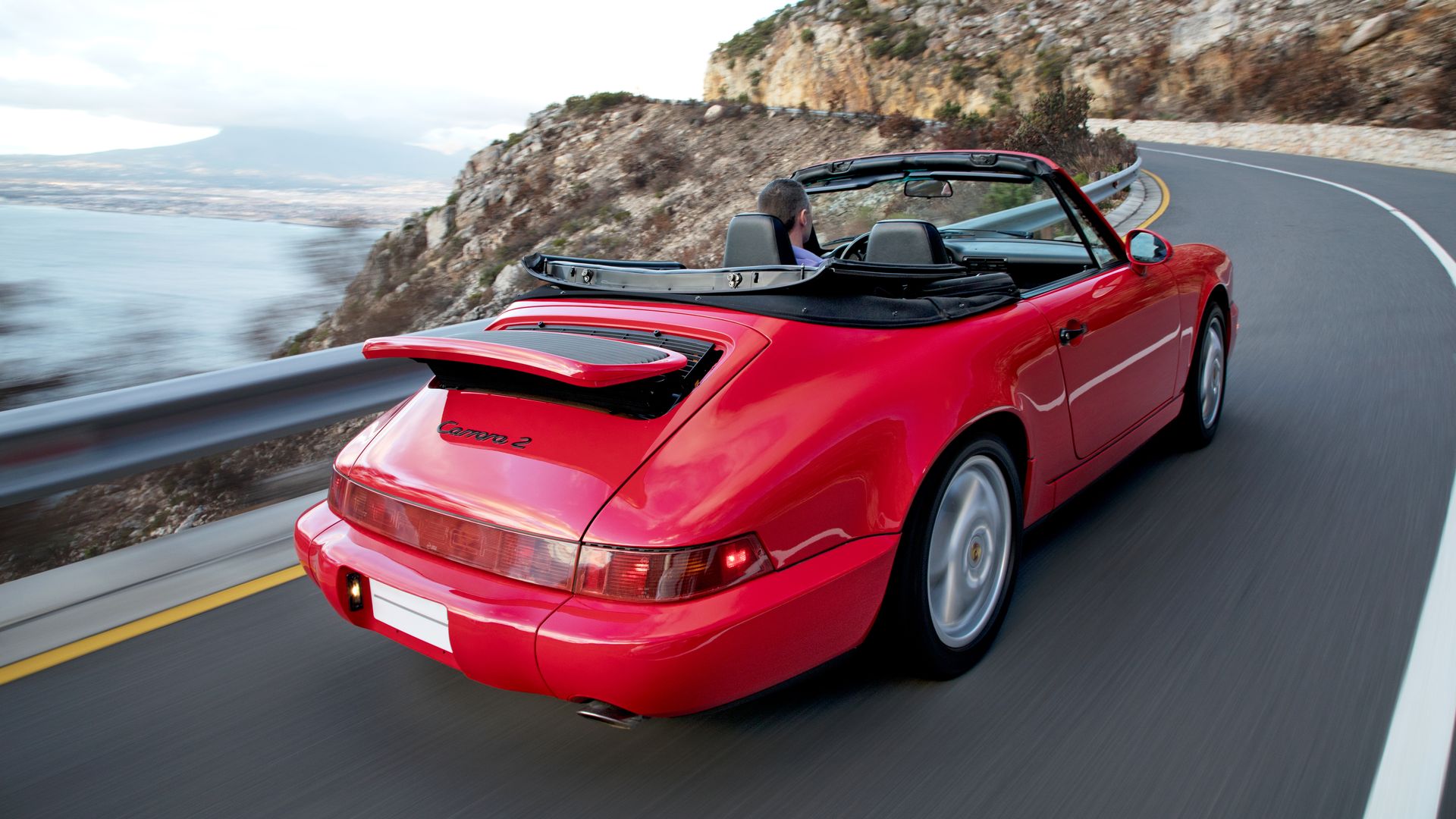 Illustration of a red Porsche driving along a coastal highway