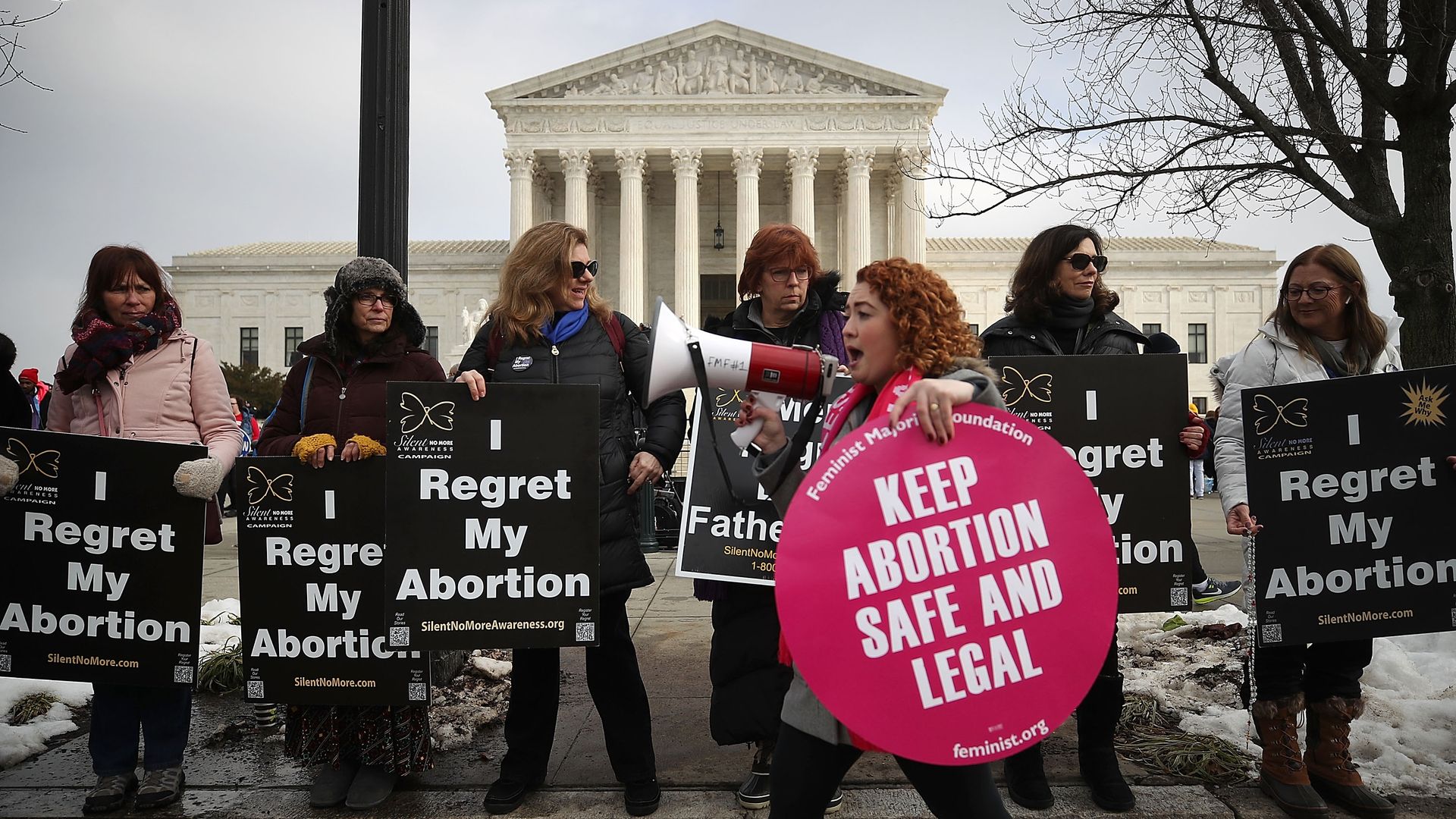 In this image, a pro-abortion protester walks past a line of anti-abortion protestors in front of the Supreme Court.