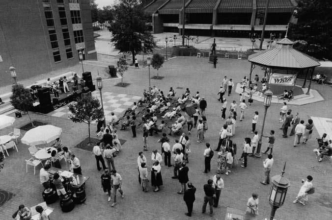 a black and white photo people of a few people standing in park in front of a band 