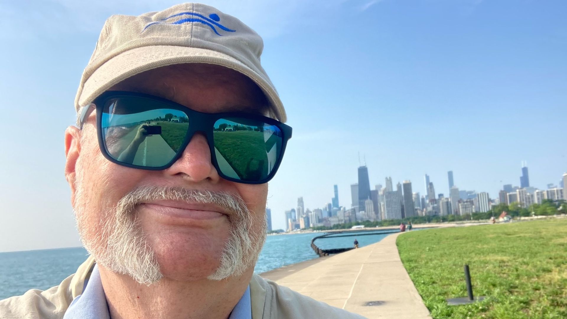 Photo of a man standing in front of a skyline near a lake.