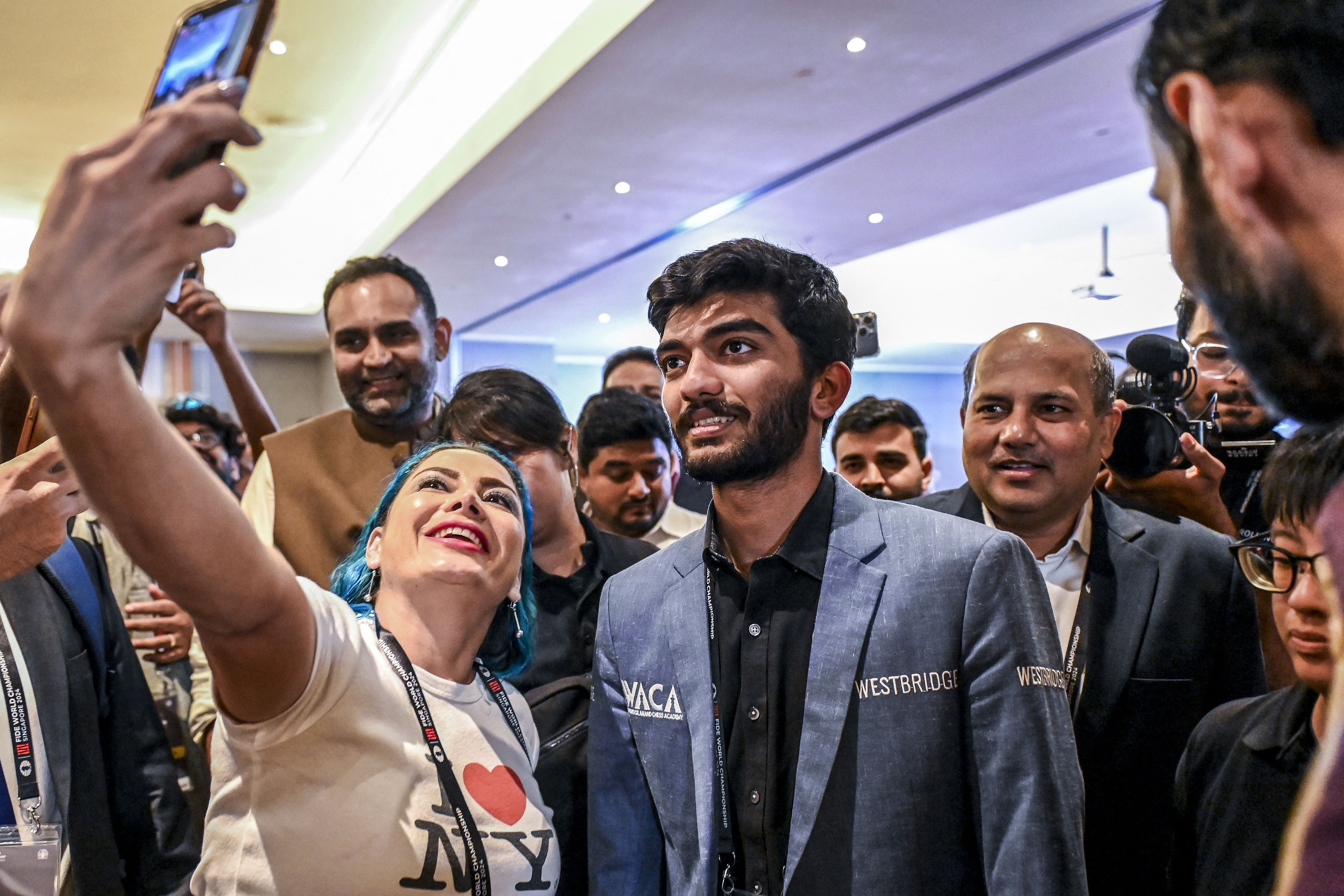 A fan takes a selfie with India's grandmaster Gukesh Dommaraju (C) after his win against China's chess grandmaster Ding Liren in game 14 of the 2024 FIDE World Championship in Singapore on December 12, 2024. 