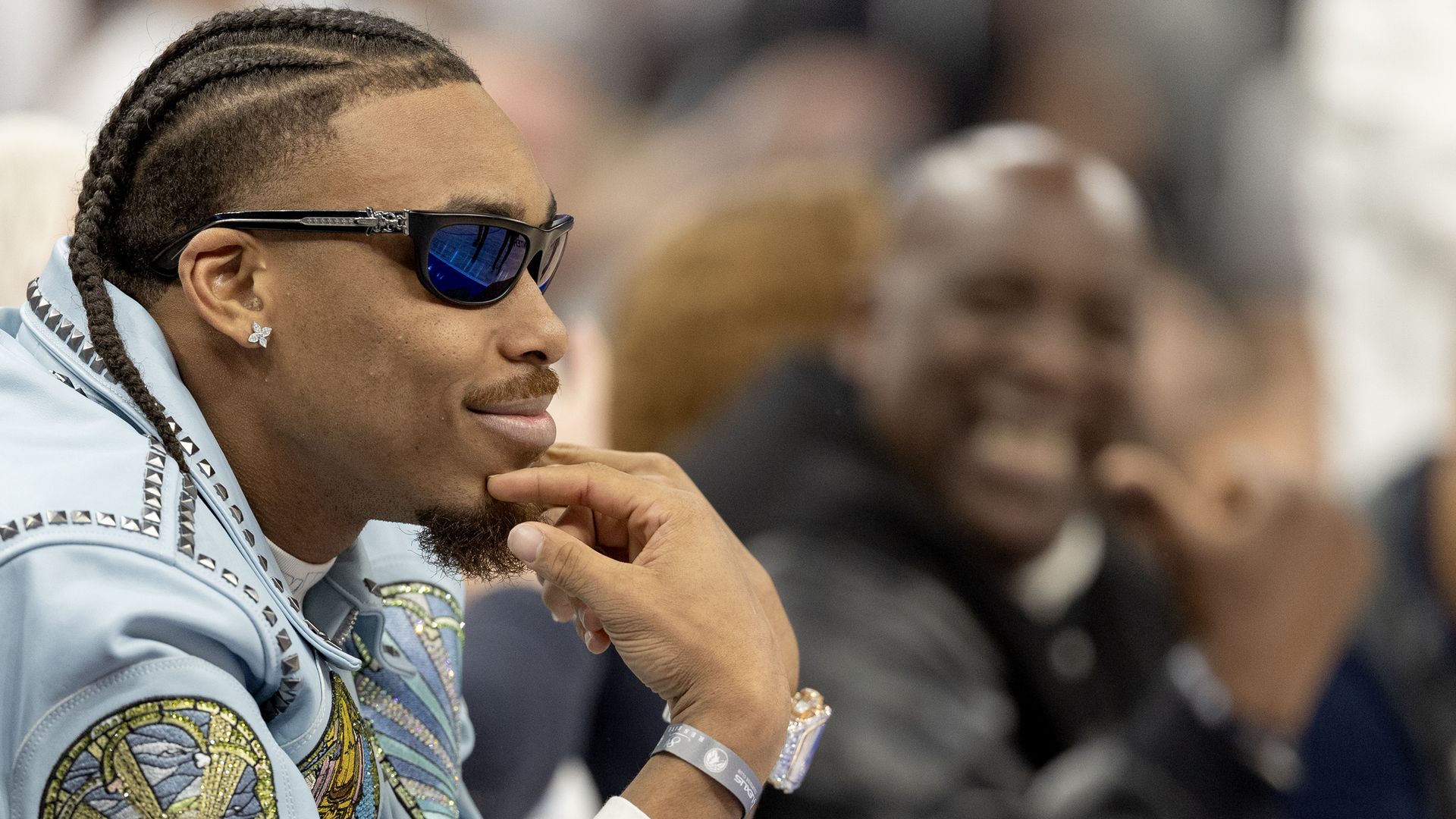 A close-up photo of Justin Jefferson, wearing sunglasses and putting his fingers on his chin, as he watches a basketball game out of the camera's view.