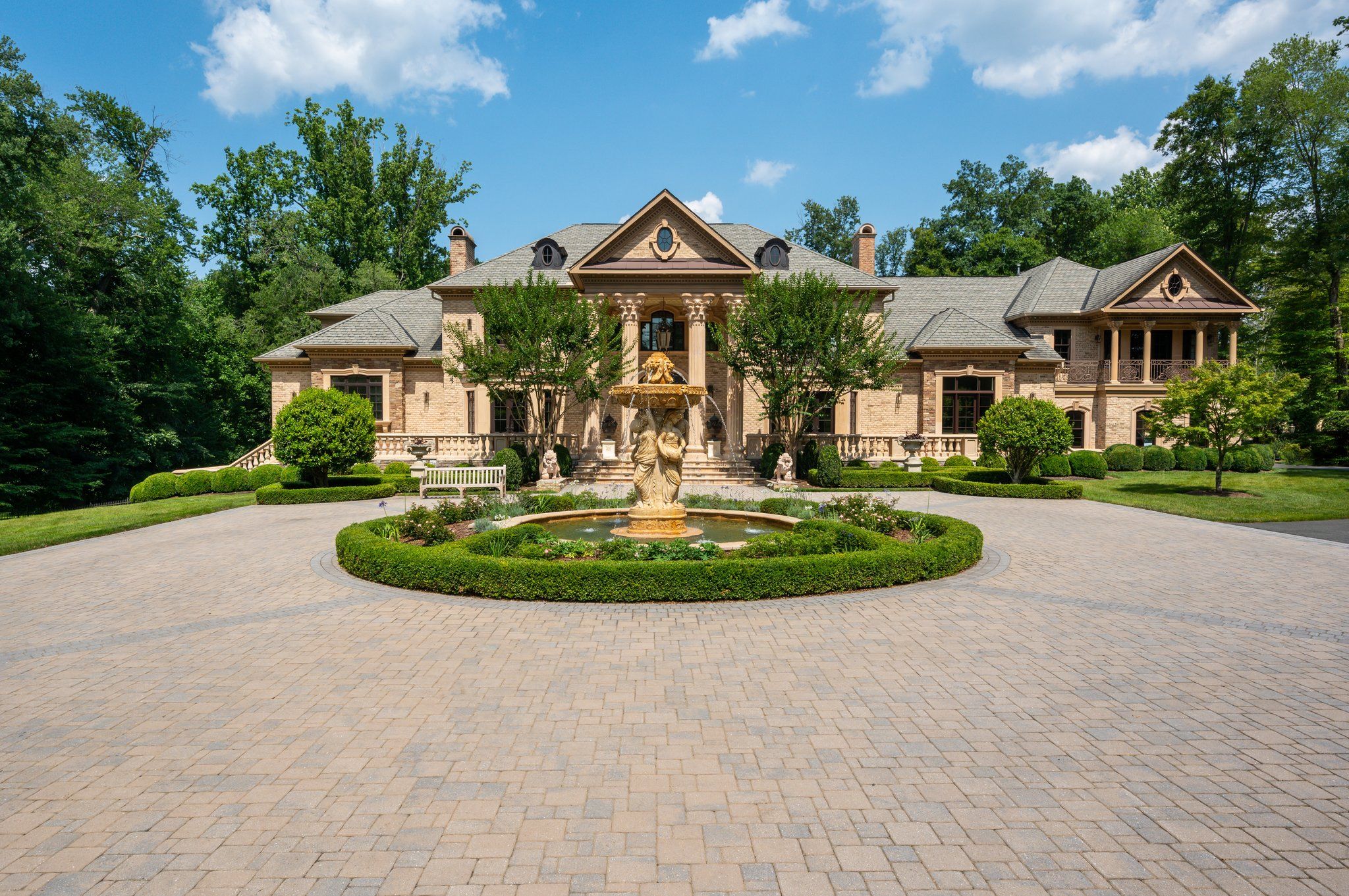 The exterior of a large home, with a motor court and fountain in front.