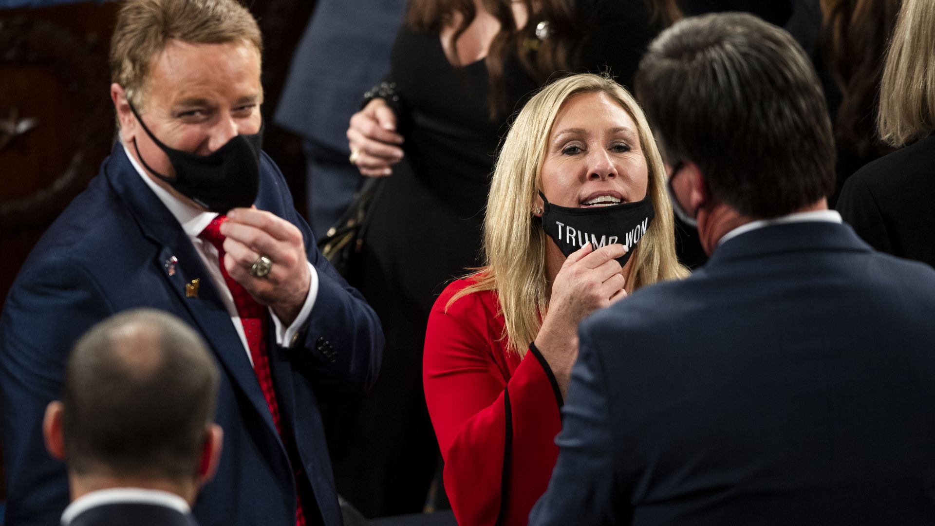 Rep. Marjorie Taylor Greene is seen pulling down her mask while speaking with a House colleague.