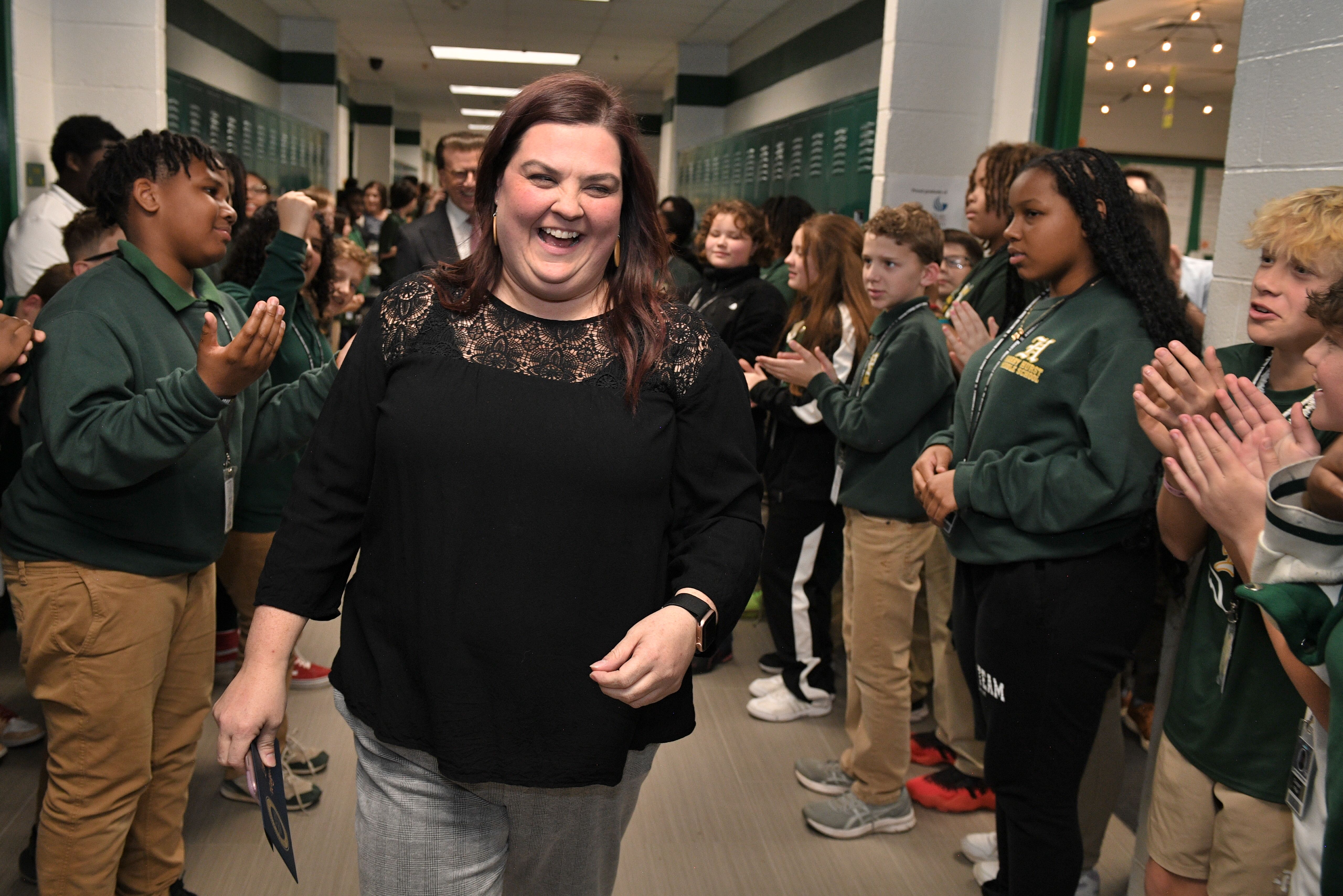 Photo shows Lauren Waguespack smiling in a school hallway with students