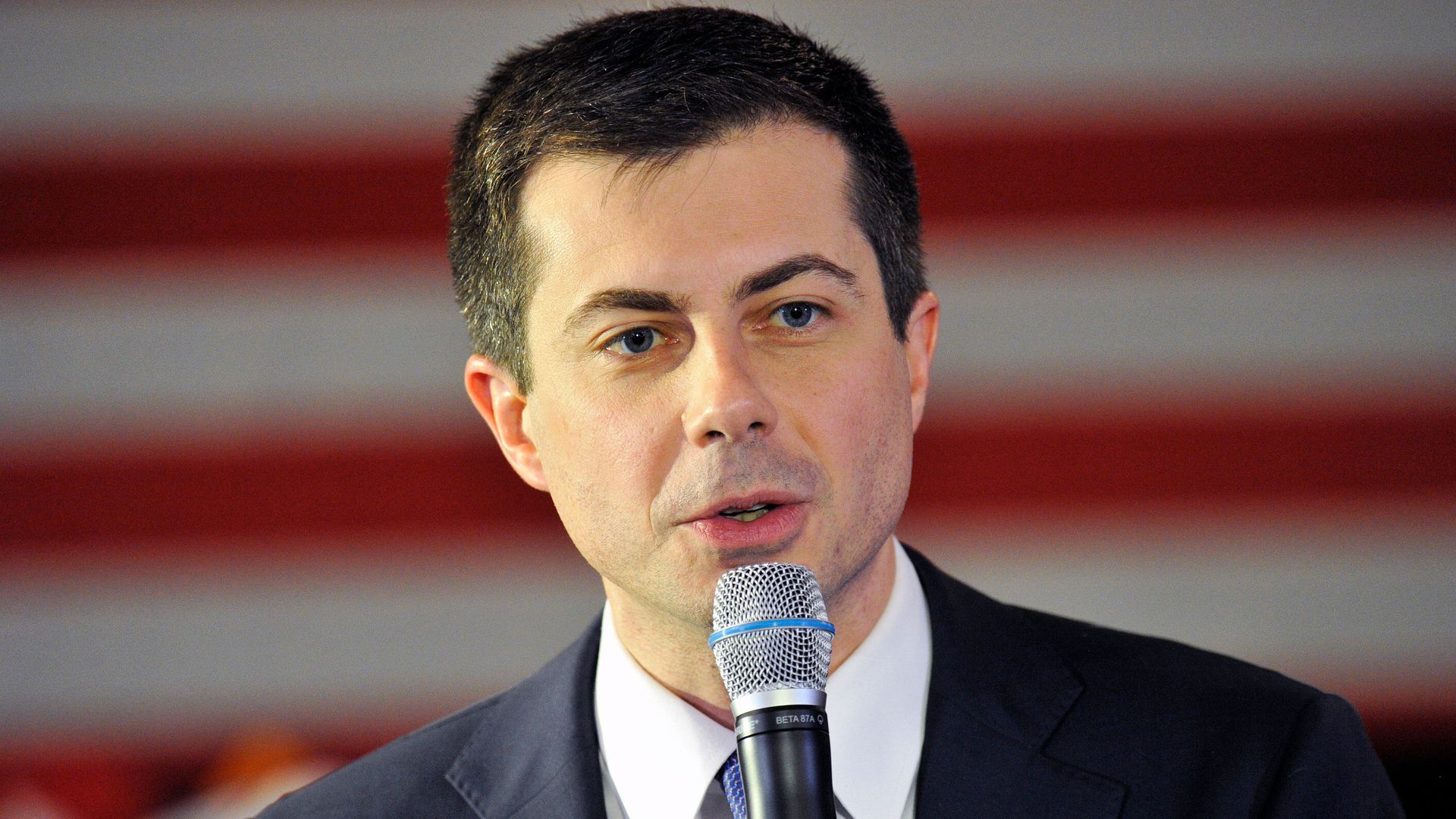 This image shows Pete speaking into a microphone and wearing a suit