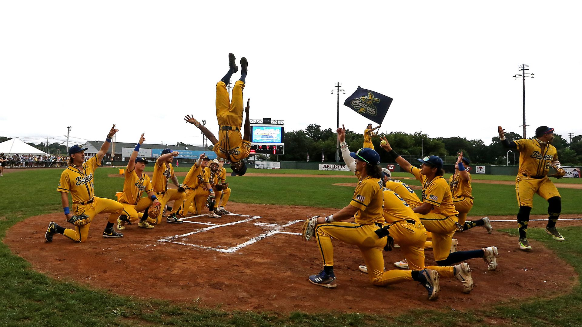 A baseball player doing a backflip at home plate.