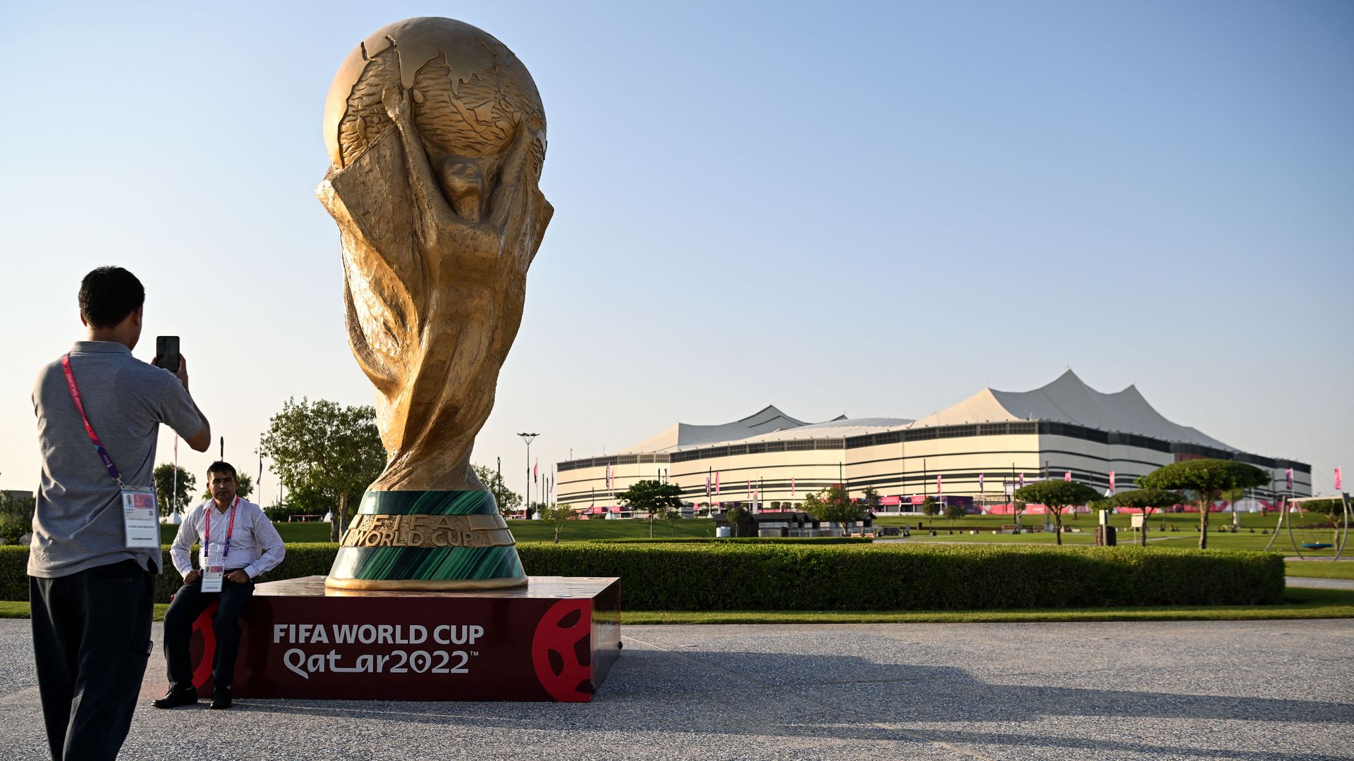 A man takes a picture of a FIFA World Cup trophy replica in front of the Al-Bayt Stadium in al-Khor on November 10, 2022, ahead of the Qatar 2022 FIFA World Cup football tournament