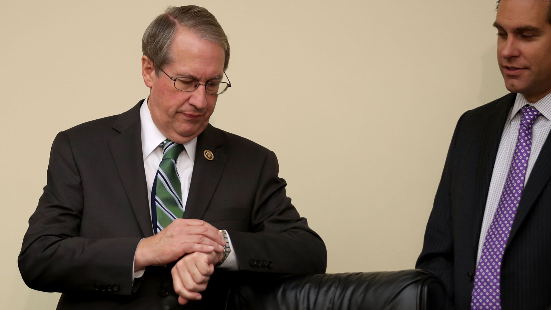 Bob Goodlatte checks his watching wearing a suit and tie