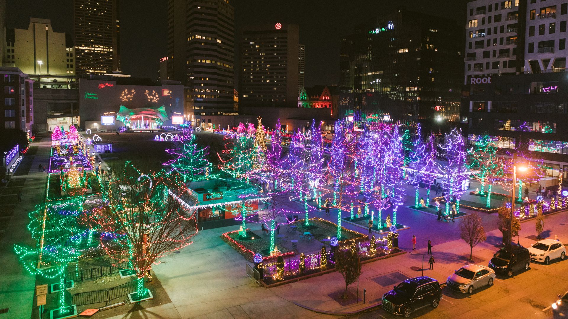 An overview of the Columbus Commons, with trees illuminated by holiday lights and the downtown skyline in the background