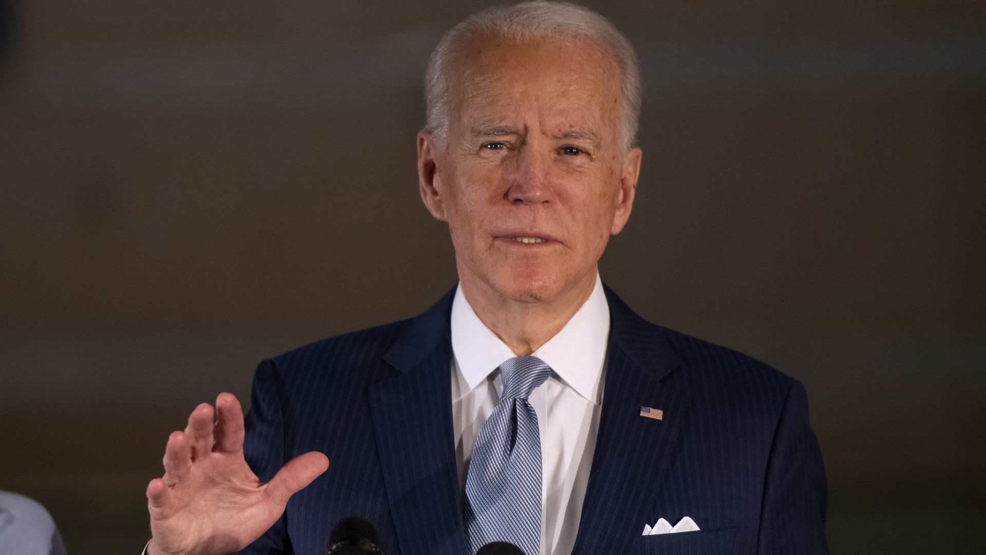 Biden stands before a microphone addressing supporters 