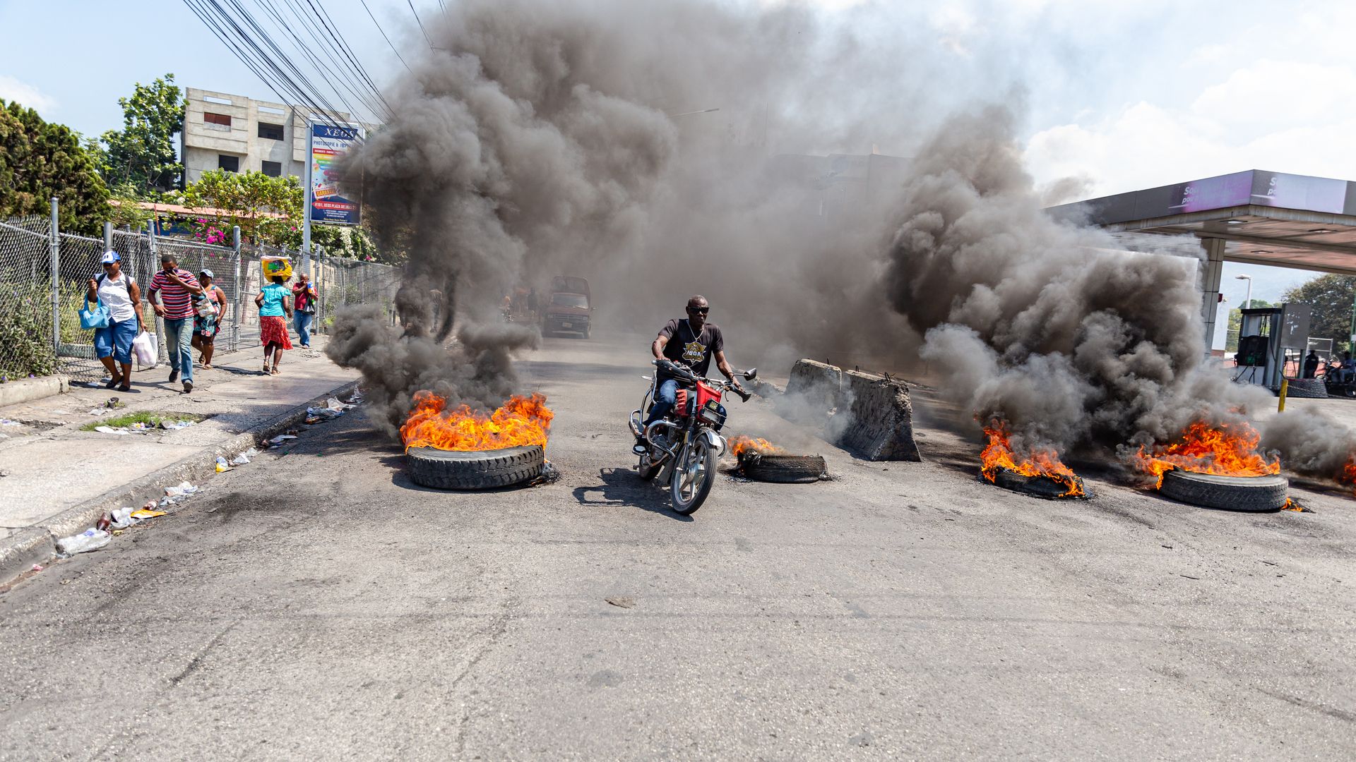 A motorcyclist passes burning tires during a demonstration 