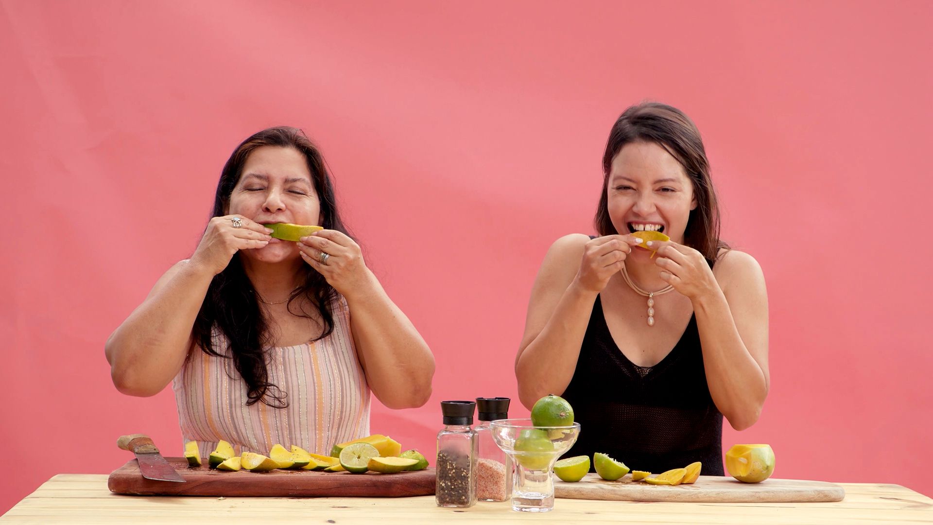 Two women eat mangoes