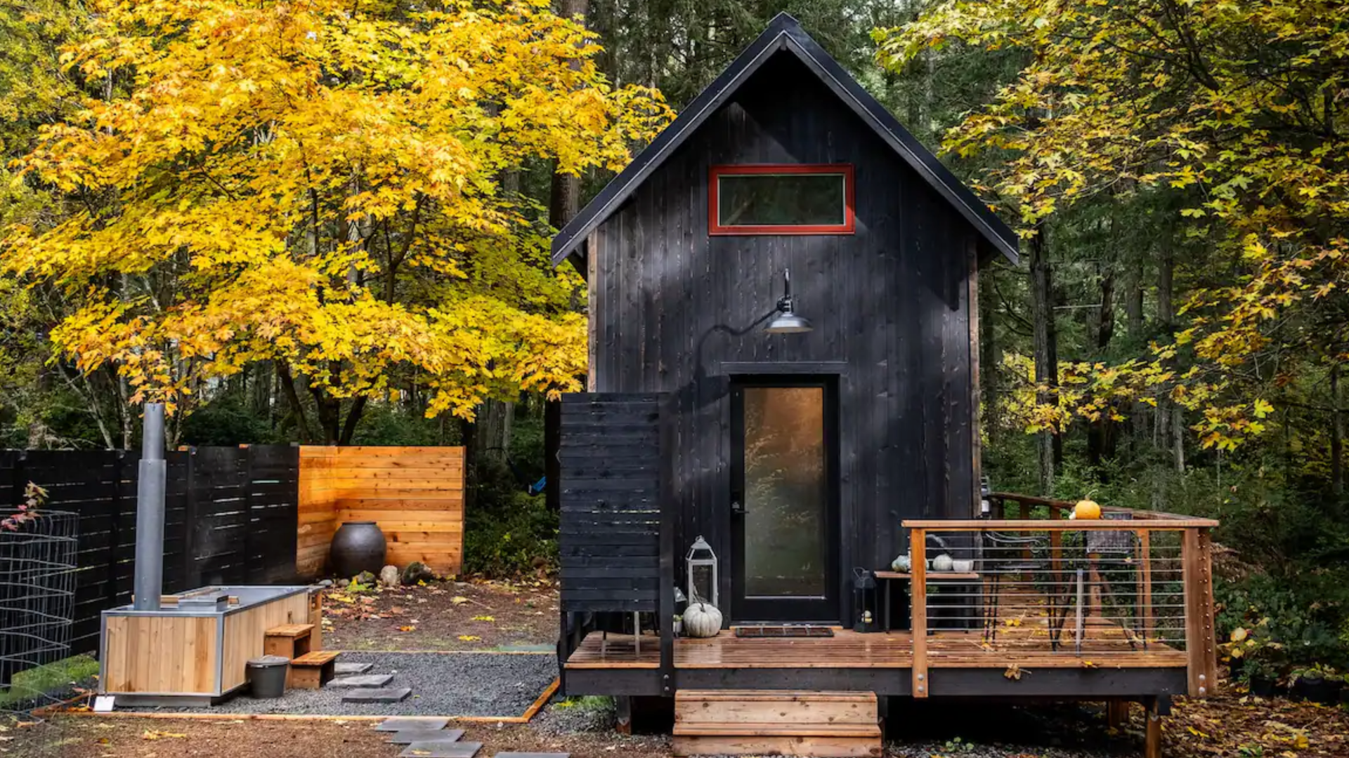 A neat little black and tan cabin in the woods.