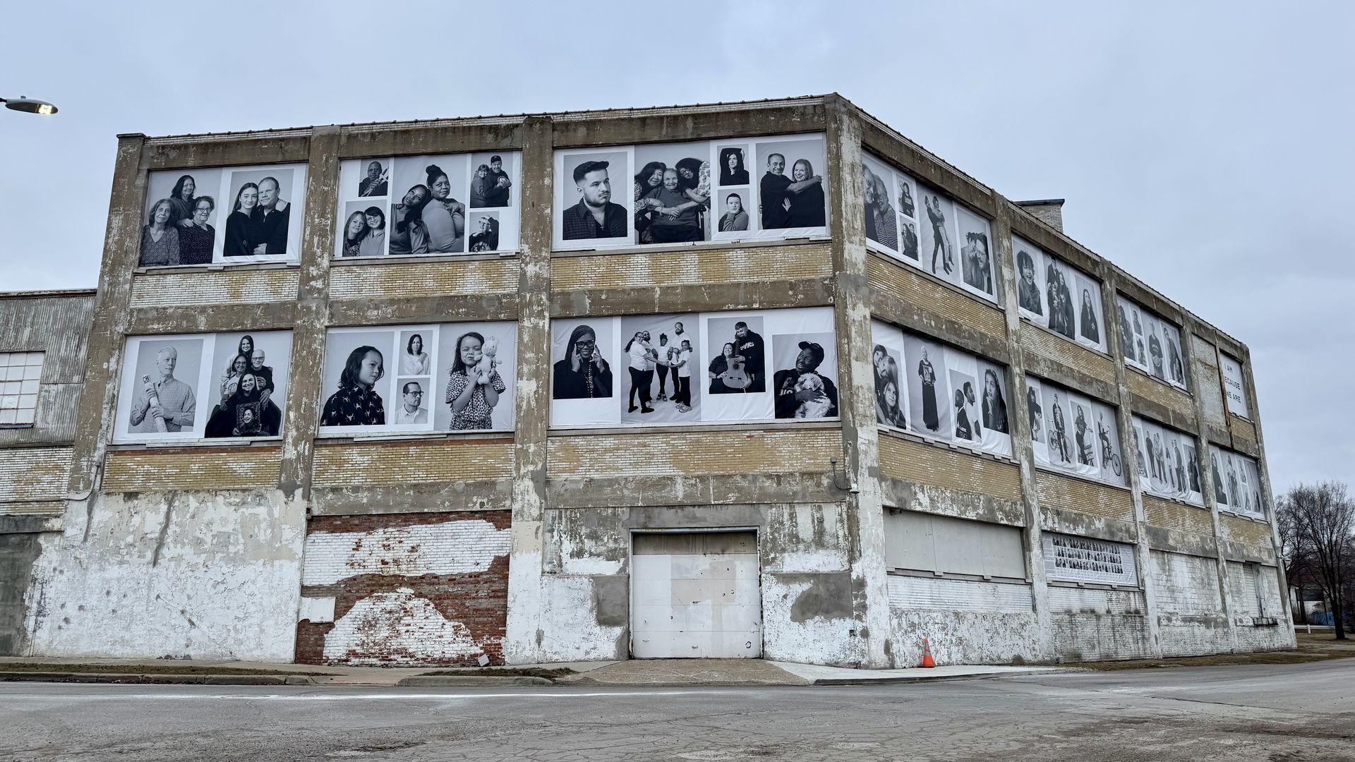 Dozens of photographs printed onto vinyl attached to the side of a building.