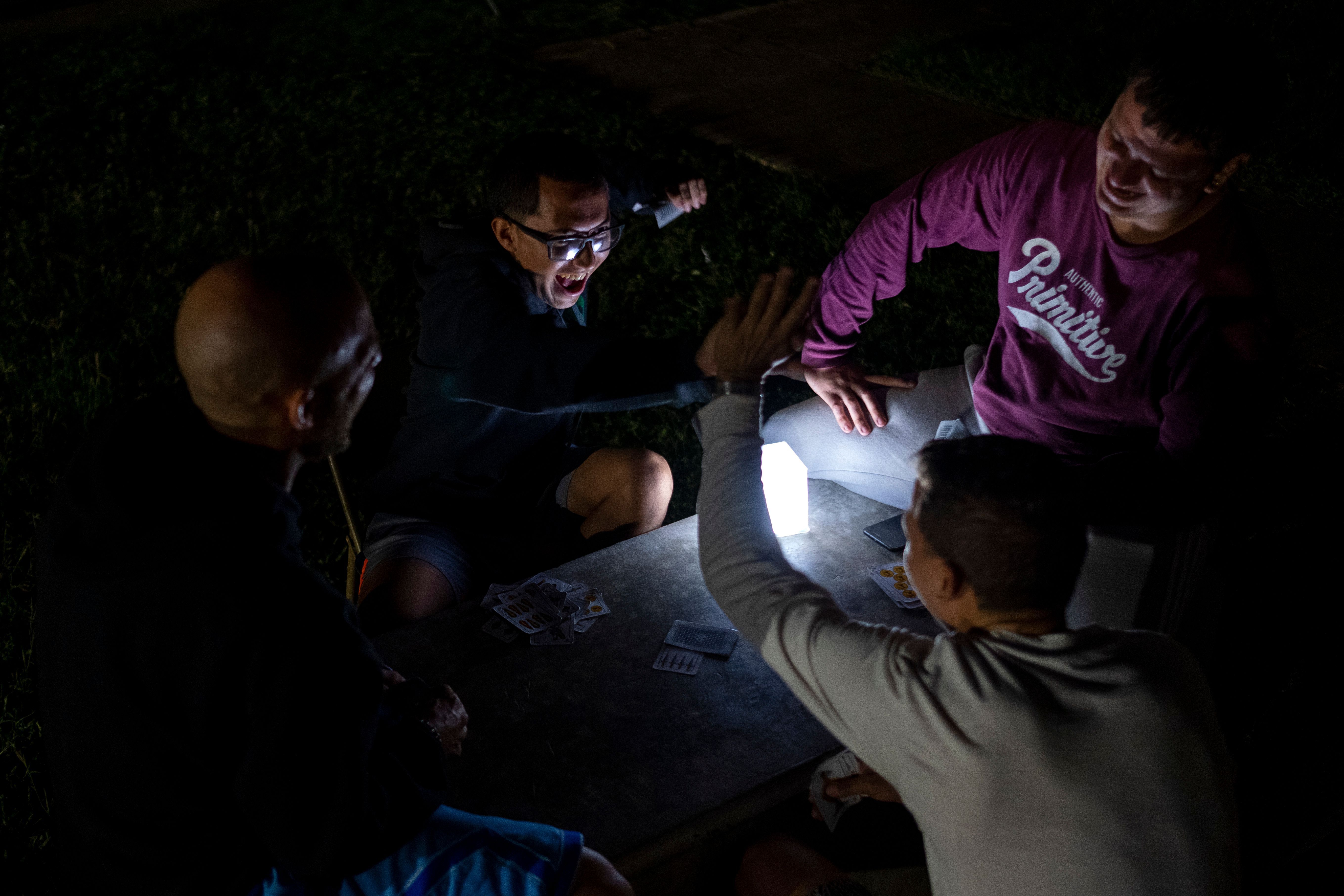 A group of young men play cards in the outdoors lit by a solar rechargeable lamp after an earthquake hit the island in Guanica, Puerto Rico
