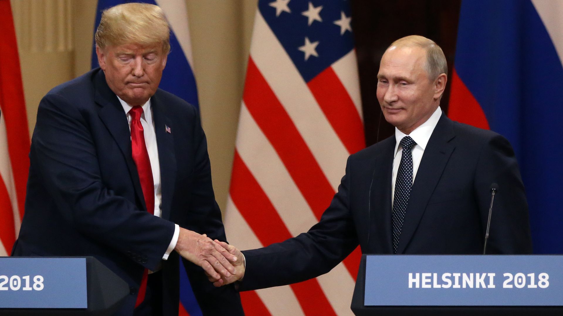 Trump and Putin shake hands while standing at podiums for press conference