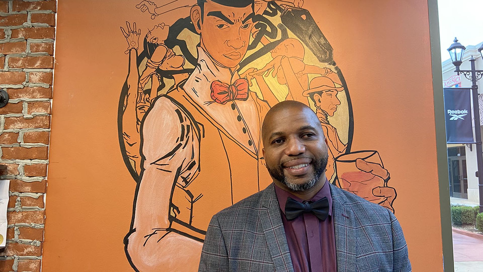 No Grease! franchise owner Edmund Washington stands in front of a mural by Marcus Kiser and Wolly McNair in his second No Grease! location.
