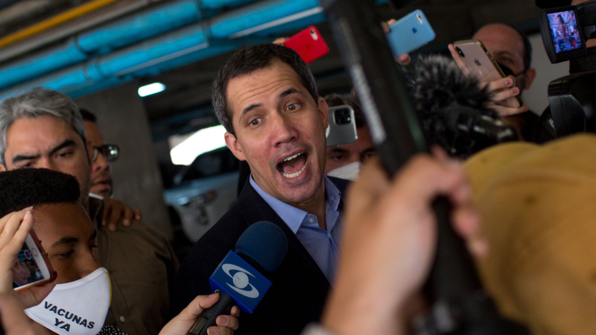 Juan Guaido, president of the National Assembly who swore himself as the leader of Venezuela, center, speaks with members of the media outside his home in Caracas, Venezuela, on Monday