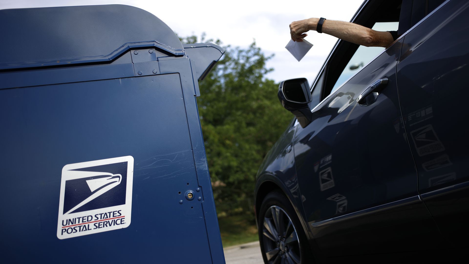 A person putting a letter in a mailbox.